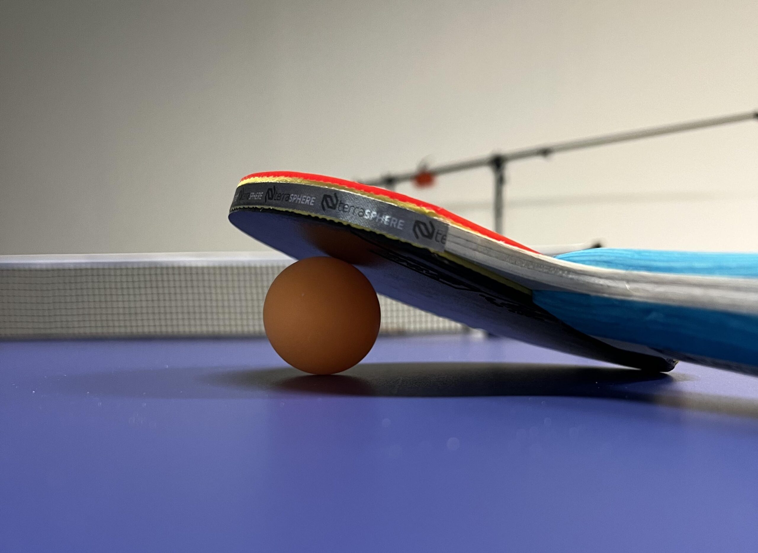 A Ping Pong Bat Rests On A Ping Pong Ball Sitting On A Ping Pong Table