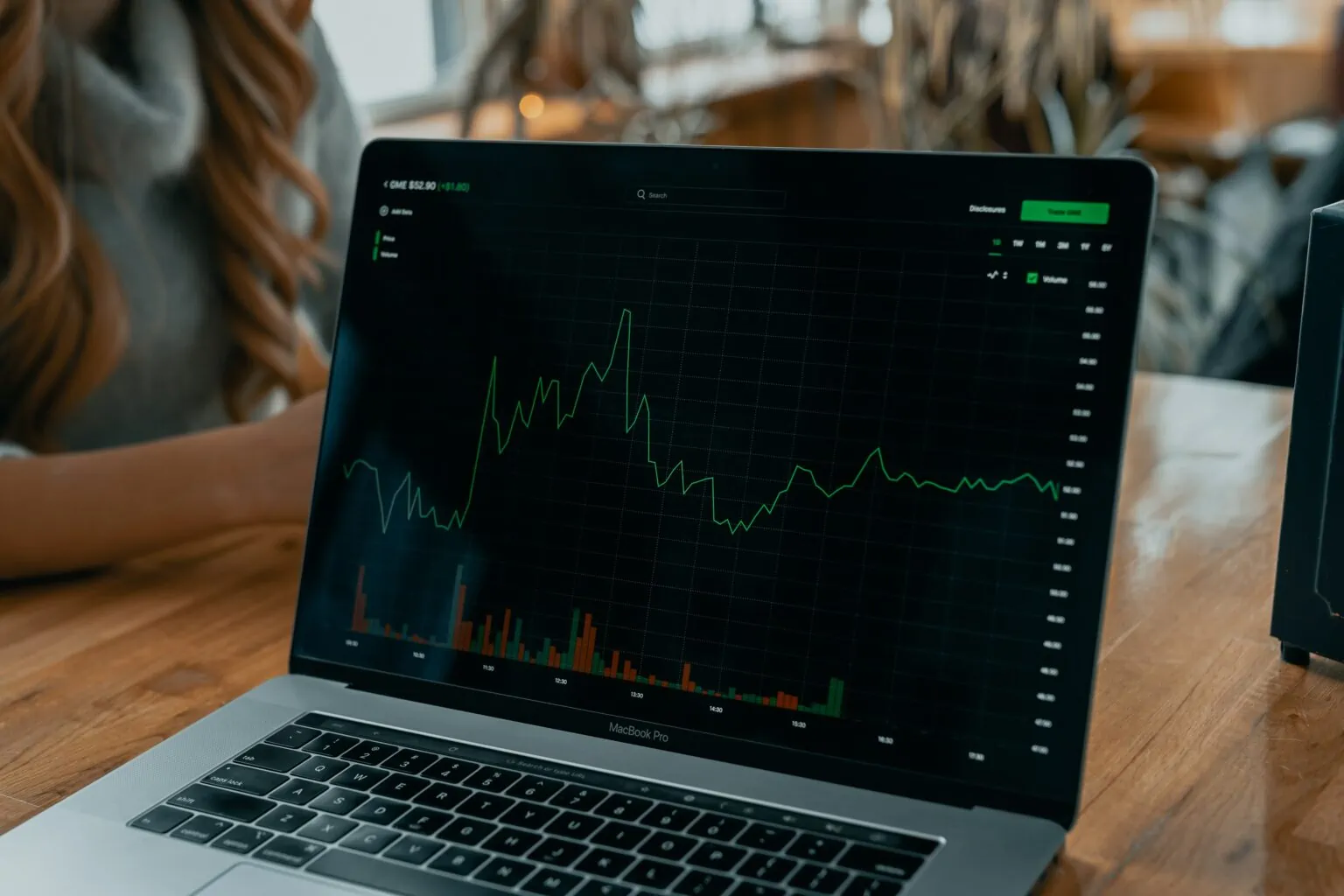 A MacBook Pro displays a stock market graph